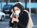 An Iranian woman wearing a protective mask checks a message on her smart phone in the Iranian capital Tehran on March 2, 2020, following the COVID-19 illness outbreak, which Iran says has claimed 66 lives.