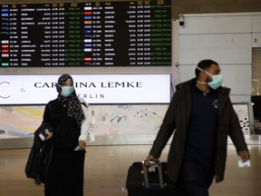 Airline passengers wearing protective face masks walk through the arrivals hall at Ben Gurion International airport in Tel Aviv on March 10.