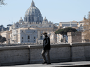 A man wearing a protective mask walks near St. Peter's Basilica in Rome.