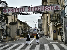 Nuns walk past the entrance to the emergencies department of the Molinette hospital in Turin on March 9, 2020 as Italy is battling the world's second-most deadly virus outbreak after China and has imposed a virtual lockdown on the north of the country.