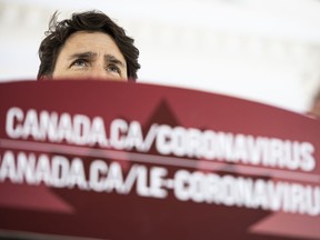 Prime Minister Justin Trudeau speaks from behind a podium bearing the hyperlink to a federal government website about the coronavirus disease during a press conference about COVID-19 in front of his residence at Rideau Cottage in Ottawa, on Sunday, March 22, 2020.