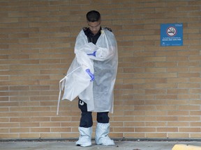 A B.C. ambulance paramedic takes off his protective clothing outside the Lions Gate Hospital in North Vancouver, B.C. Monday, March 23, 2020.