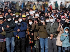 People wear protective face masks following the outbreak of the coronavirus disease (COVID-19) as they try to watch the Olympic cauldron during the Tokyo 2020 Olympic's Flame of Recovery tour at Ishinomaki Minamihama Tsunami Recovery Memorial Park in Ishinomaki, Miyagi prefecture, Japan March 20, 2020.