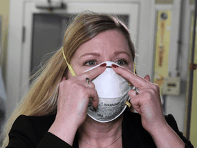 Dr. Nicole McCullough, a global health and safety expert at 3M, demonstrates the correct way to put on a N95 respiratory mask.