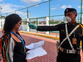 A member of the Institutional Protection Service of Panama checks the temperature of an employee of Las Garzas Presidential Palace in Panama City on March 12, 2020.