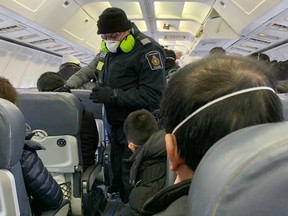 A Royal Canadian Mounted Police (RCMP) officer wearing a mask checks Canadians, who had been evacuated from China due to the outbreak of novel Coronavirus on an American charter plane, on another aircraft taking them to Canadian Forces Base (CFB) Trenton, from Vancouver International Airport in Richmond, British Columbia, Canada February 7, 2020.