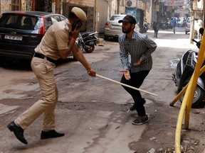 A police officer wields his baton against a man as a punishment for breaking the lockdown rules after India ordered a 21-day nationwide lockdown to limit the spreading of coronavirus disease (COVID-19), in New Delhi, India, March 25, 2020.