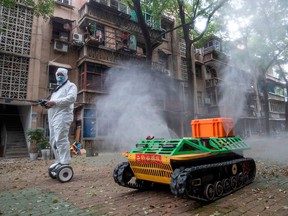 A volunteer uses a remote-controlled disinfection robot to disinfect a residential area in Wuhan, China, amid the COVID-19 coronavirus outbreak, on March 16, 2020.
