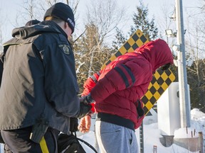 A young man from Yemen is handcuffed by an RCMP officer after crossing the border from the U.S. into Canada near Hemmingford, Que., on Friday, February 17, 2017. For many asylum-seekers, Roxham Road in the small Quebec town of Hemmingford represents the first steps of a potential new life.