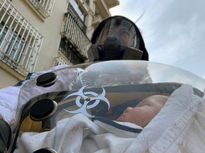 A man poses for a photo with his two-month-old baby inside a safety pod he created to protect him from COVID-19, at a residential compound in Shanghai, China, on March 25, 2020.