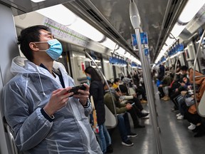 Passengers wearing face masks travel on a subway train in Shanghai on March 5, 2020.