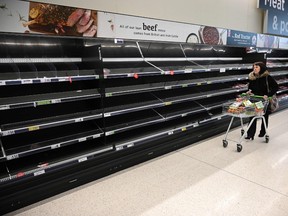 A shopper walks past empty food shelves amidst the novel coronavirus COVID-19 pandemic, in Manchester, northern England on March 20, 2020.