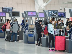 Travellers wearing masks check in at the Canadian Domestic departure area at Toronto Pearson Airport's Terminal 1 during continued concerns of the Covid 19 virus, Monday March 16, 2020.