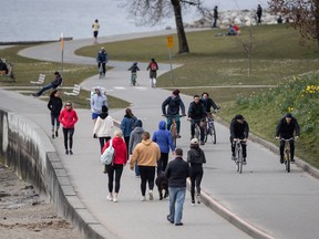 People walk and cycle on the seawall between English Bay and Sunset Beach, in Vancouver, on Sunday, March 22, 2020. The City of Vancouver asked those using parks and beaches to maintain a distance of 2 metres between one another due to concerns about the spread of COVID-19.