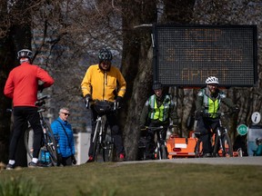 A sign warns people to social distance and keep at least 2 metres apart from one another due to concerns about the spread of the coronavirus, as park rangers and others bike and walk on the seawall, in Vancouver, on Wednesday, March 25, 2020. As government agencies across Canada focus strained resources on protecting people from COVID-19, efforts to respond to freedom-of-information requests from the public are slowing or even stopping altogether.THE CANADIAN PRESS/Darryl Dyck