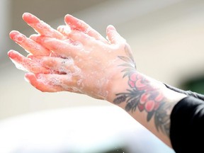 A patron washes their hands at the hand washing station at the entrance of the Safe Supply outdoor grocery store at Bow Market in Somerville, Mass., March 21, 2020.