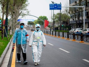 TOPSHOT - A couple wearing protective suits as a preventive measure against the COVID-19 coronavirus walk along a street in Wuhan in China's central Hubei province on March 31, 2020.
