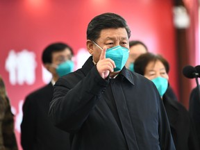 This photo released by China's Xinhua News Agency shows Chinese President Xi Jinping wearing a mask as he gestures to a coronavirus patient and medical staff via a video link at the Huoshenshan hospital in Wuhan, in China's central Hubei province on March 10, 2020.
