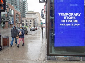 Pedestrians walk past a closed store in Montreal on March 30.