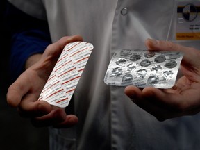 In this file photo taken on February 26, 2020 a medical staff shows at the IHU Mediterranee Infection Institute in Marseille, packets of a Nivaquine, tablets containing chloroquine and Plaqueril, tablets containing hydroxychloroquine.