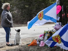 Denise Caume and her dog, Mimi, are seen in front of the makeshift memorial, made in the memory of Sunday’s mass shooting in Portapique, Nova Scotia, Canada April 23, 2020.