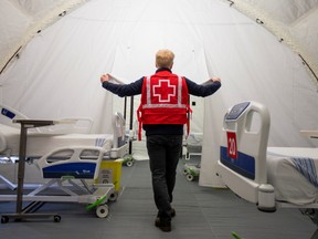 A volunteer with the Red Cross shows a doorway between beds in a mobile hospital set up in partnership with the Canadian Red Cross in the Jacques-Lemaire Arena to help care for patients with the coronavirus disease (COVID-19) from long-term centres (CHSLDs), in Montreal, Quebec, Canada April 26, 2020. x