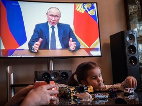 A woman watches a live broadcast of Russian President Vladimir Putin's address to the nation over the coronavirus outbreak, in her appartment in Moscow on April 2, 2020.