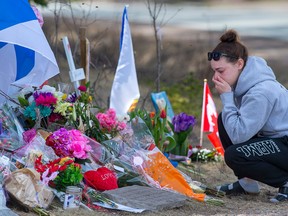 A woman pays her respects at a roadside memorial on Portapique Road in Portapique, N.S. on Friday, April 24, 2020.