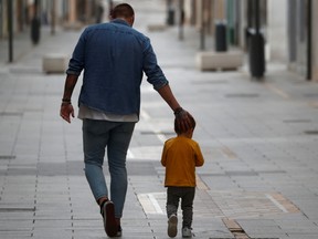 A man and his son take a walk in the empty La Bola street, after restrictions were partially lifted for children for the first time in six weeks, during the coronavirus disease (COVID-19) outbreak in Ronda, Spain, April 26, 2020.