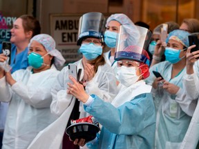 Healthcare workers react to people applauding in front of the Mount Sinai Hospital in Queens to show gratitude to medical staff and essential workers on the front lines of the coronavirus pandemic, April 15, 2020 in Queens, New York City.