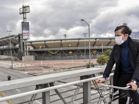 A person wearing a face mask rides his bicycle in front of El Campin stadium during quarantine on April 21, 2020 in Bogota, Colombia.