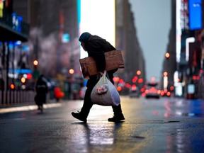 A man carries cardboard as he crosses the almost deserted Times Square on April 13, 2020 in New York City.