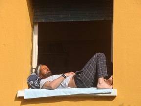 A man sunbathes on the windowsill of his home window on March 22, 2020 in Rome, Italy.