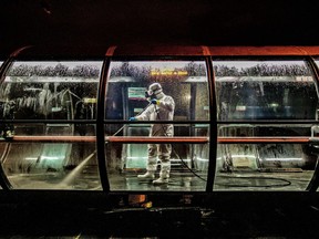 A volunteer worker disinfects a public bus station in Curitiba on early April 1, 2020, against the new coronavirus, COVID-19.