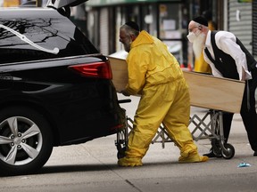 Orthodox Jewish men move a wooden casket from a hearse at a funeral home in the Borough Park neighborhood which has seen an upsurge of (COVID-19) patients during the pandemic on April 05, 2020 in the Brooklyn Borough of New York City.