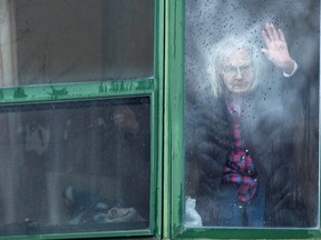 A resident waves from her window at Residence Herron, a senior's long-term care facility, following a number of deaths since the coronavirus disease (COVID-19) outbreak, in the suburb of Dorval in Montreal Quebec, Canada, April 13, 2020.