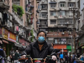 A man wearing a face mask ride a scooter on a street in Wuhan, China's central Hubei province on April 14, 2020.