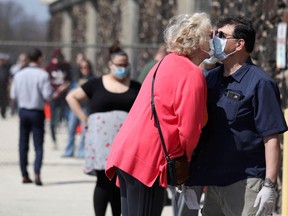 Voters Jeff Tragitz, right, and Lori Walter kiss while wearing mask masks as they wait in line outside a polling station at Hamilton High School during the presidential primary election, held amid the coronavirus disease (COVID-19) outbreak, in Milwaukee, Wisconsin, U.S., April 7, 2020.