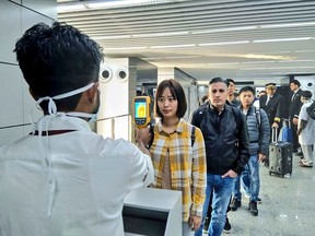 A man (L) uses a thermographic camera to screen the head of people at Netaji Subhash Chandra Bose International Airport in Kolkata, January 2020.