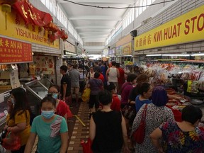 Customers visit a wet market to buy food in Singapore on April 4, 2020, with some people wearing face masks due to concerns over the spread of the COVID-19 coronavirus.