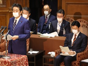 Japanese Prime Minister Shinzo Abe, left, delivers a report to committee members of the Lower House in Tokyo on April 7, before declaring a state of emergency due to the COVID-19 pandemic.