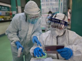 Medical workers check information as they take swab samples from people to be tested for the COVID-19 novel coronavirus in Wuhan, China's central Hubei province on April 16, 2020.