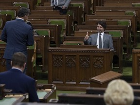 Prime Minister Justin Trudeau gives the thumbs up as he speaks with a Member of Parliament as they wait for the COVID-19 committee in the House of Commons Chamber Wednesday April 29, 2020 in Ottawa.