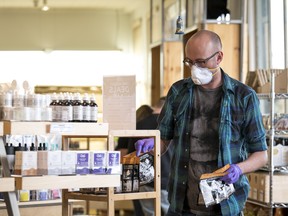 An employee wearing a protective face mask and gloves arranges products on a shelf at a dispensary in Oakland on March 23.