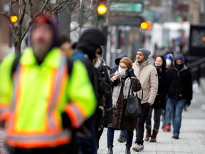 A woman adjusts her mask while she waits in line as the city's public health unit holds a walk-in clinic testing for coronavirus disease (COVID-19) in Montreal, Quebec, Canada March 23, 2020.