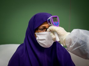 A medical worker conducts a patient temperature check in a temporary coronavirus hospital at Iran Mall in Tehran, Iran, on Monday, April 13, 2020. Iran is seeking to gain access to $1.6 billion in assets that had been frozen in Luxembourg to help fight the coronavirus outbreak.