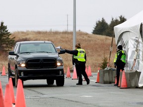 A Nova Scotia conservation officer passes a paper to a person crossing into the province from New Brunswick in its effort to prevent the spread of the coronavirus disease (COVID-19) at the Fort Lawrence, Canada April 2, 2020.