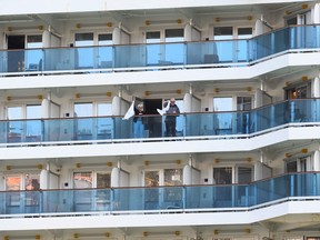 Passengers aboard the Costa Luminosa cruise ship, that was hit by the coronavirus disease (COVID-19), wave from a balcony, at the port of Savona, near Genoa, in Italy, March 21, 2020.