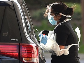 A medical staff member administers a test for the novel coronavirus COVID-19 at a drive-in facility set up in the carpark of Chessington World of Adventures in Chessington, Greater London on March 28, 2020.