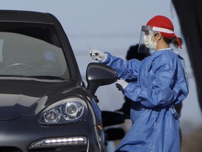 A healthcare worker administers a Covid-19 test at a drive through testing facility in Toronto, on Wednesday, April 22.